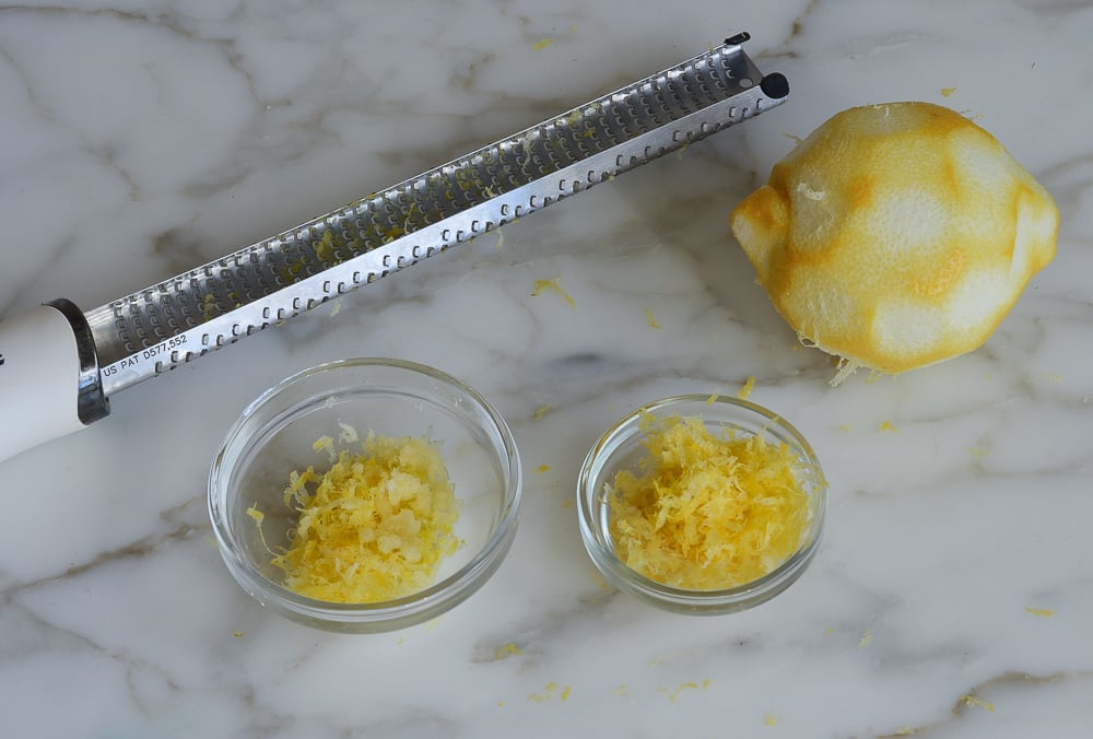 Bowls of lemon zest with a microplane grater and a zested lemon.