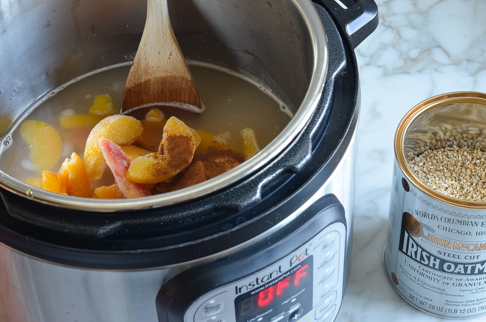 Peaches and seasonings added to an Instant Pot of steel-cut oats.