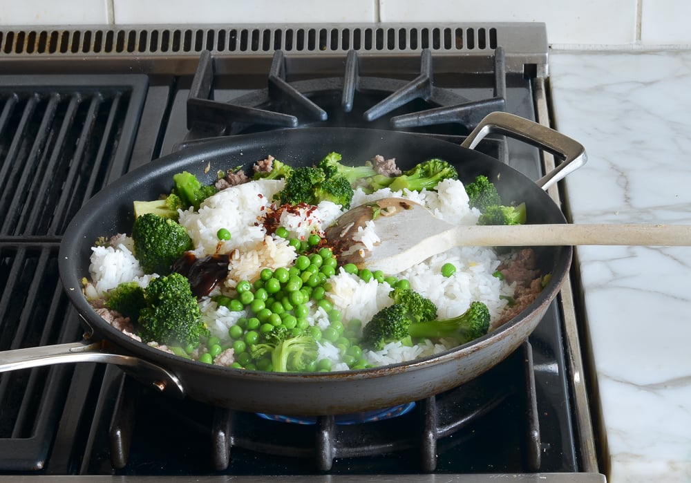 Rice and vegetables in a skillet with ground pork.