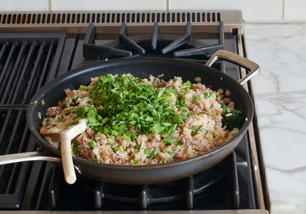 Scallions and cilantro in a skillet with rice.