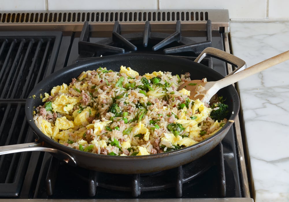 Scrambled eggs in a skillet with a rice mixture.