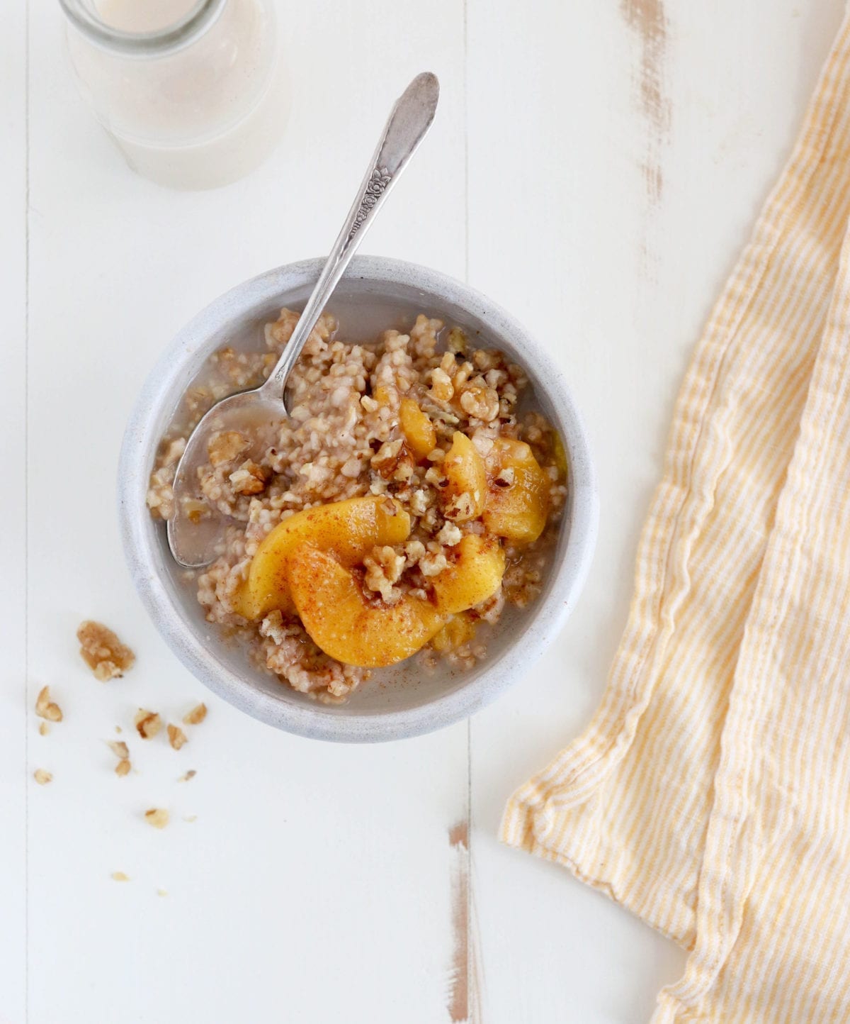 Spoon in a bowl of peaches and cream steel-cut oatmeal.