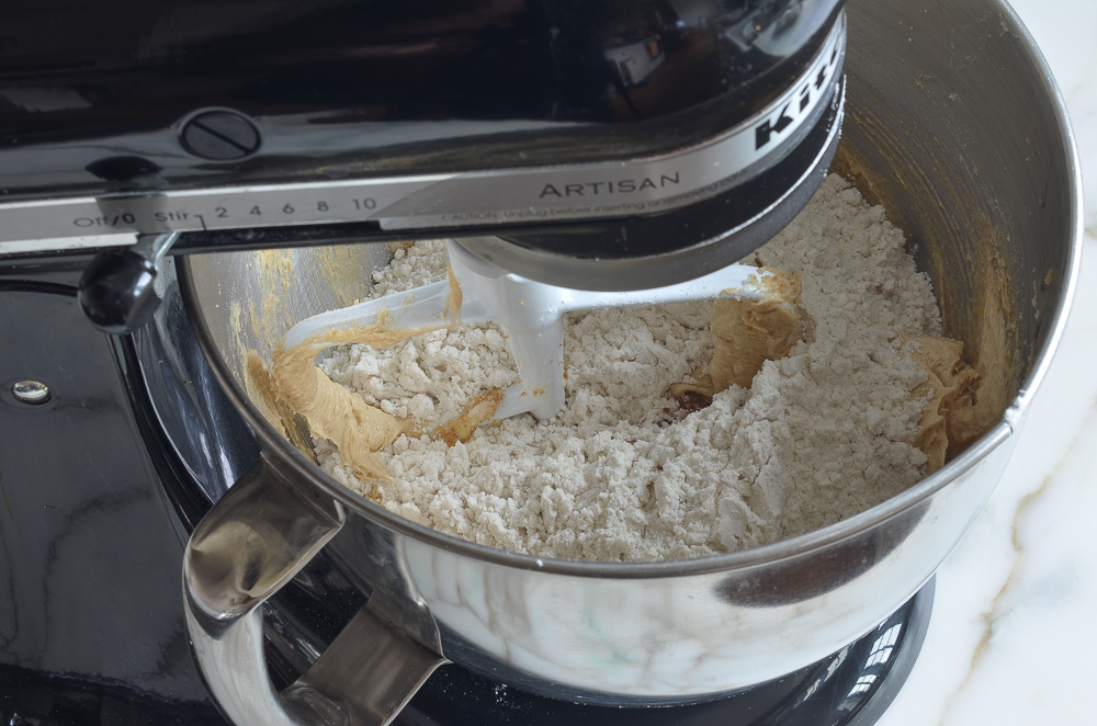 Dry ingredients added to a stand mixer of butter mixture.