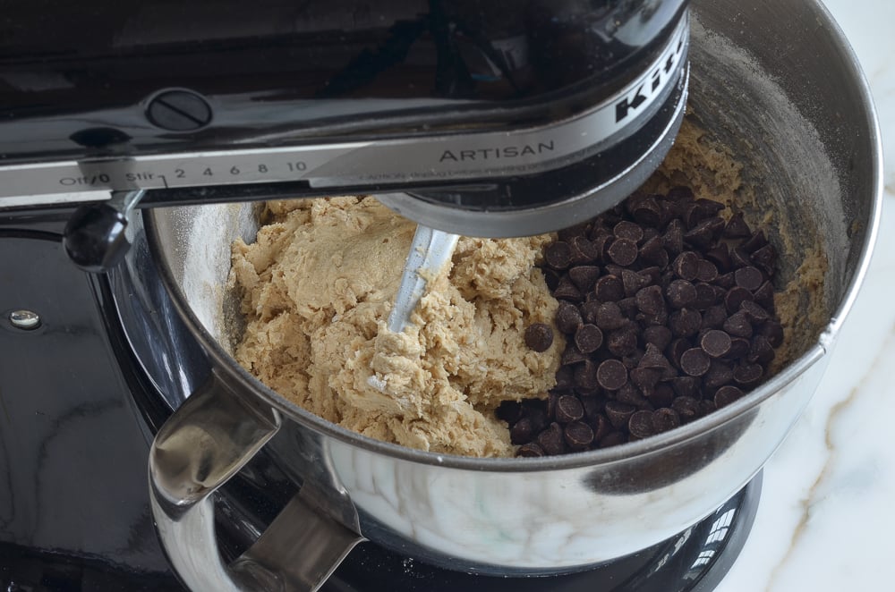Chocolate chips in a stand mixer with cookie dough.