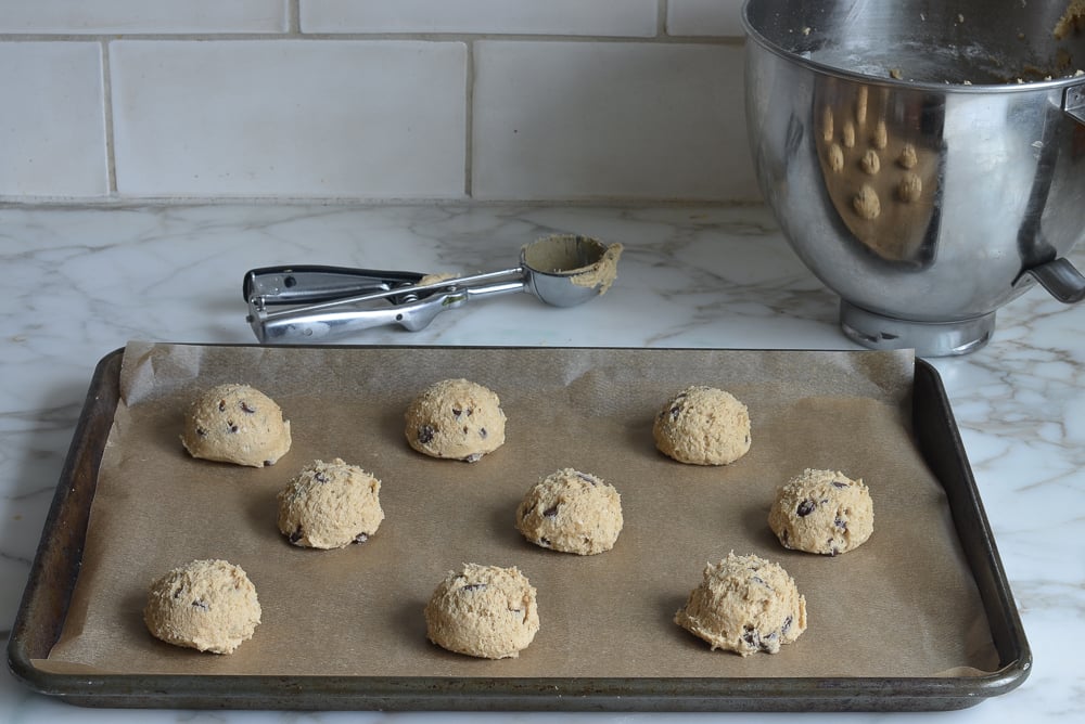 Balls of Gluten Free Chocolate Chip Cookie dough on a lined baking sheet.