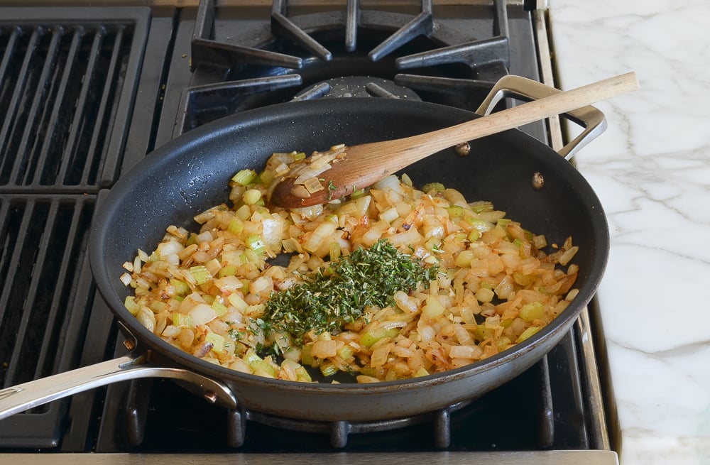 adding the herbs to the vegetables