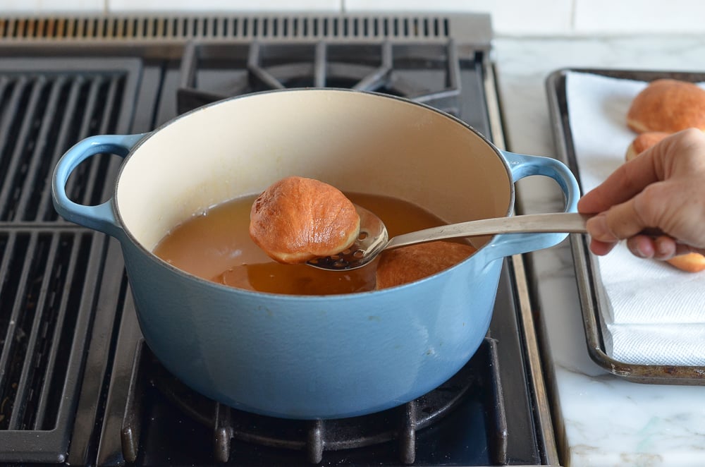 Spoon removing fried dough from a Dutch oven.