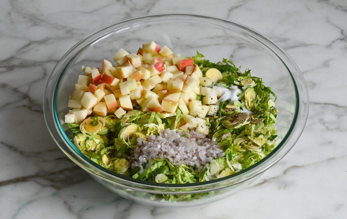 Brussels sprouts, apples, shallots, and dressing ingredients in mixing bowl