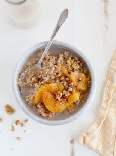 Spoon in a bowl of peaches and cream steel-cut oatmeal.