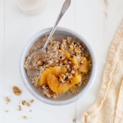 Spoon in a bowl of peaches and cream steel-cut oatmeal.