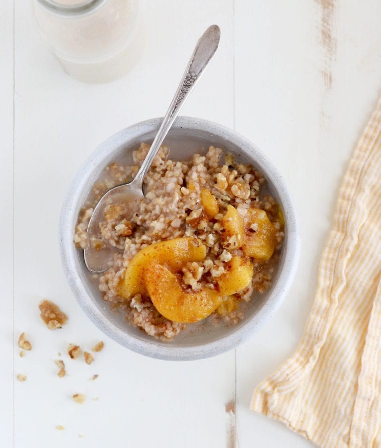 Spoon in a bowl of peaches and cream steel-cut oatmeal.