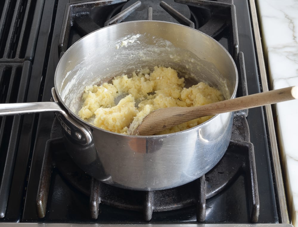 Wooden spoon in a pan with dough.