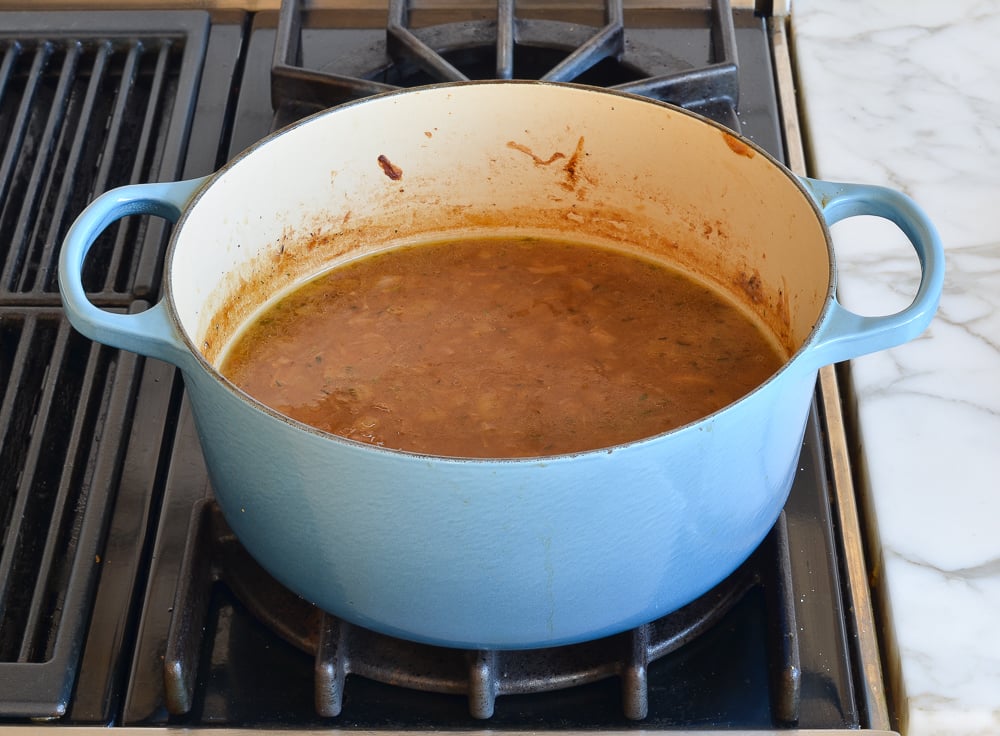 Rich French onion soup broth in Dutch oven.