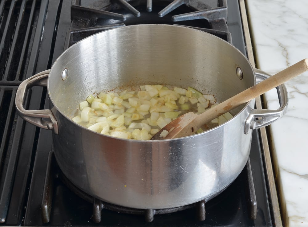 Wooden spoon in a pan of onions.