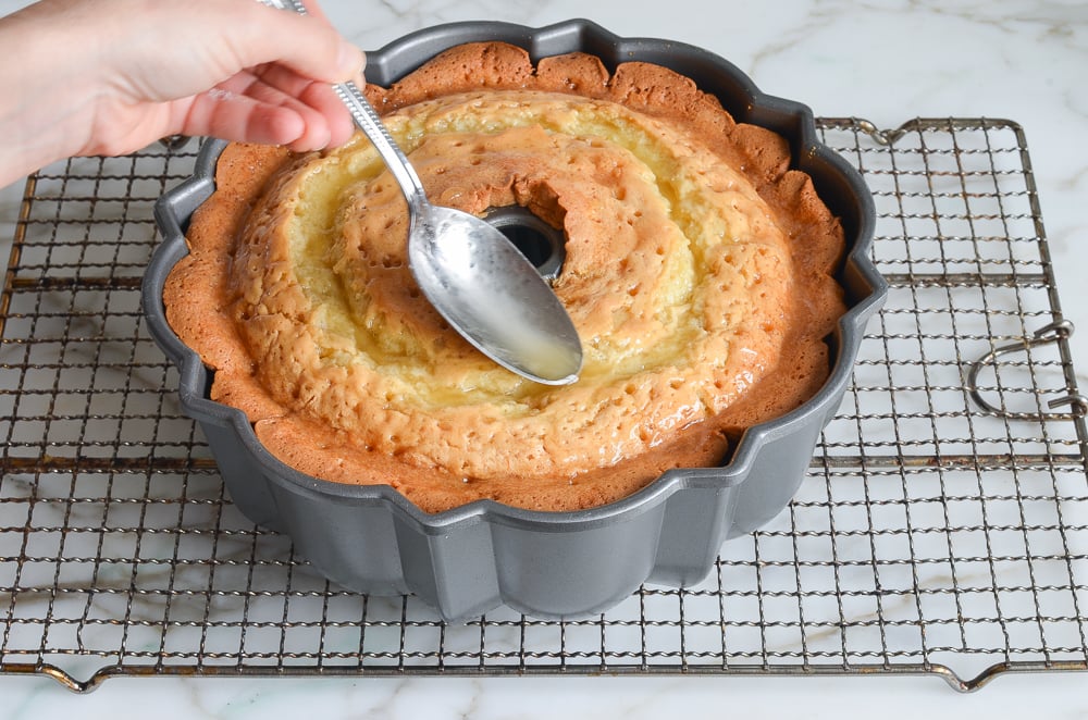 spooning glaze over cake