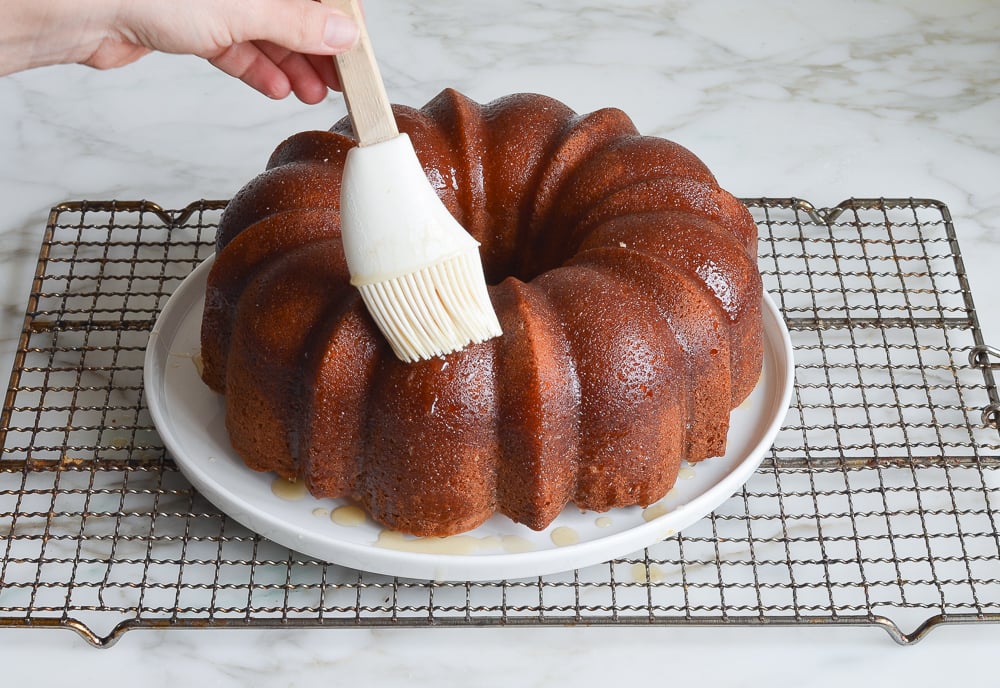 brushing the glaze over the top of the cake