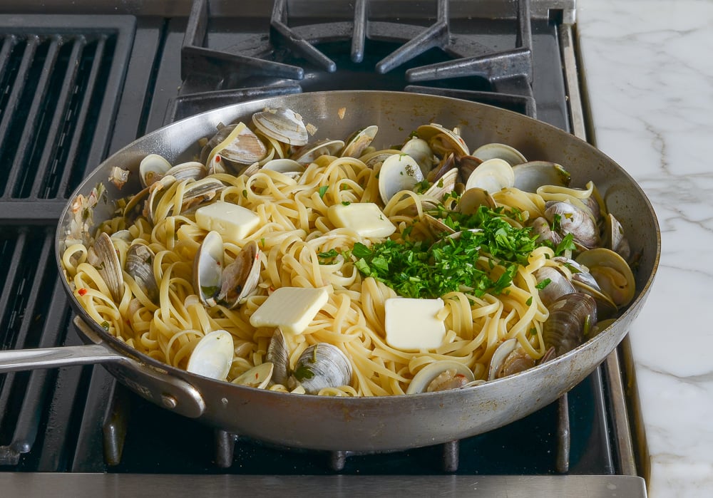 adding butter, lemon, and parsley to the pasta