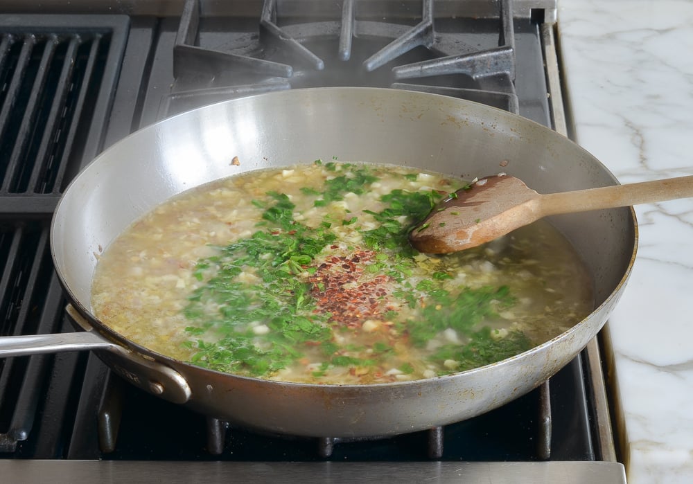 adding wine, parsley and chili flakes to pan