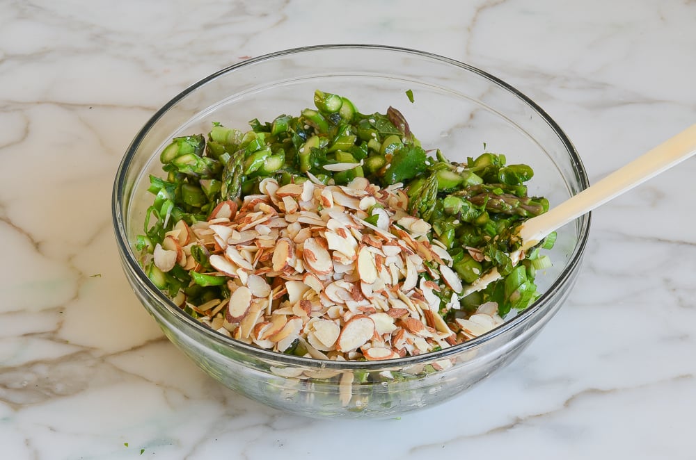 adding almonds to asparagus salad