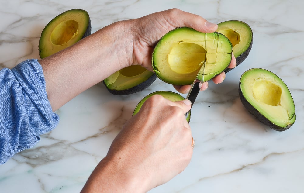 Cutting a grid in the avocado flesh.