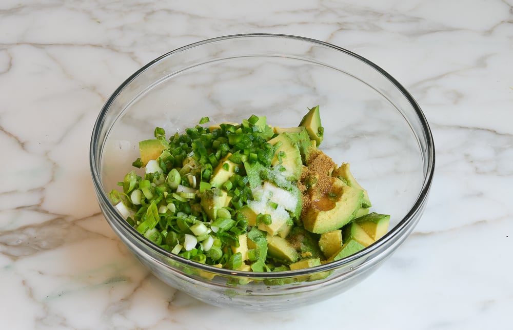 Avocado, jalapeno, scallions and cumin added to mixing bowl.