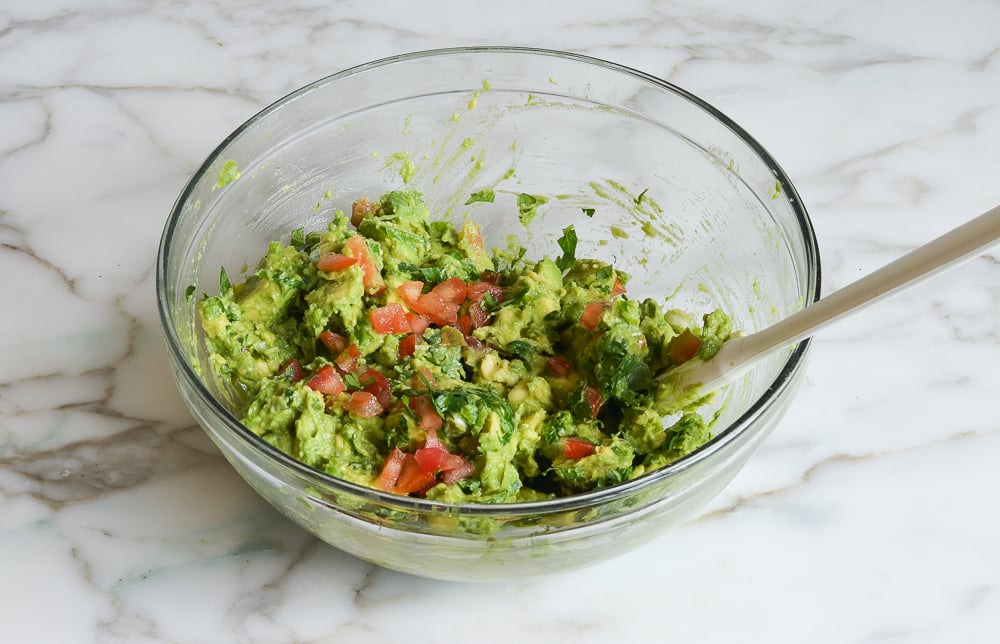 Folding in tomatoes and cilantro to make the best guacamole.