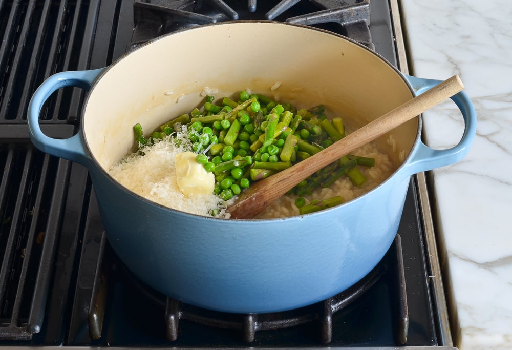 adding the cooked vegetables, cheese and butter to the risotto
