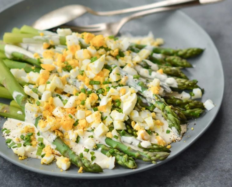Plate of asparagus salad with hard-boiled eggs and creamy dijon dressing.