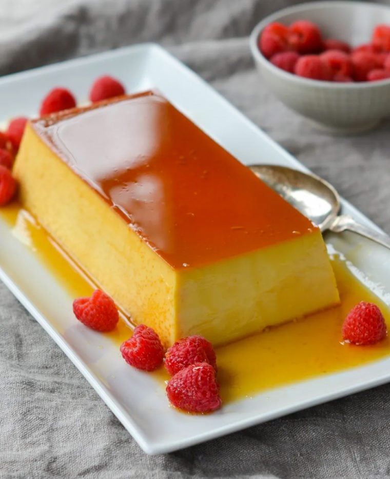 Best flan recipe served on a rectangle platter with raspberries.