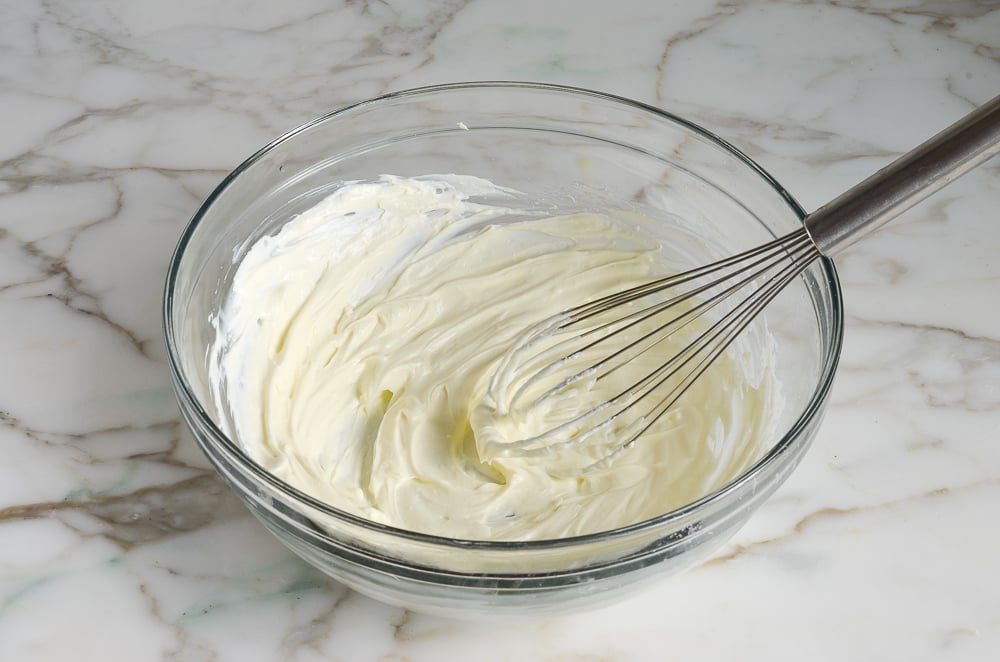 Whisking warm cream cheese until smooth