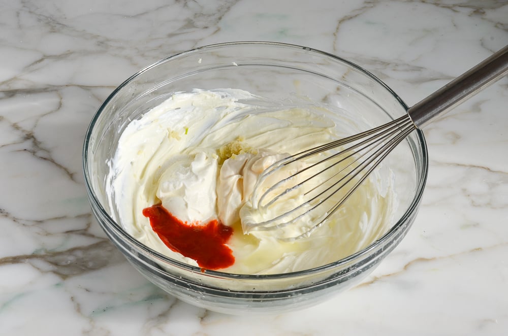 adding sour cream, mayonnaise, sriracha, garlic, lime, salt and sugar to warm cream cheese