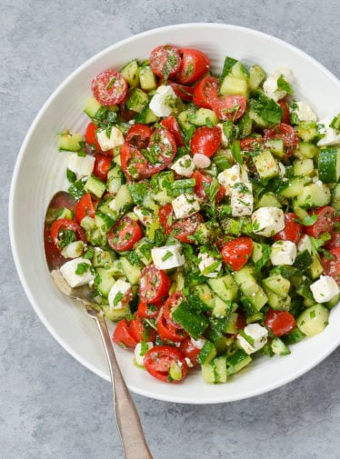 Spoon on a plate with Israeli salad with feta.