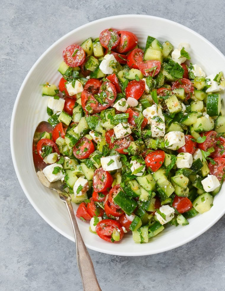 Spoon in a large plate of Israeli salad.