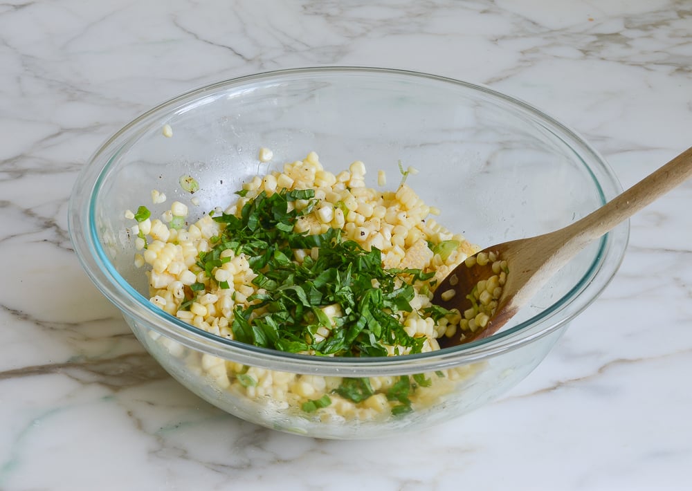 adding basil to corn salad