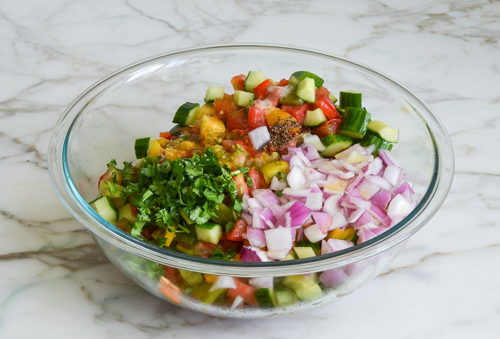 adding soaked onions, cilantro, seasoning, and dressing for gazpacho salad