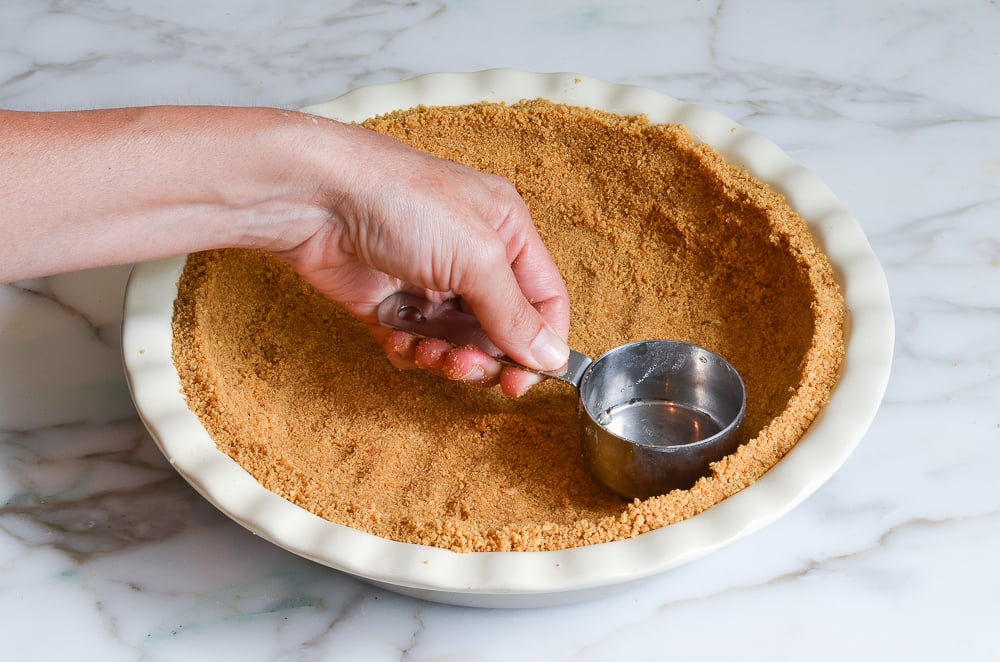 pressing the graham cracker crust into pie pan