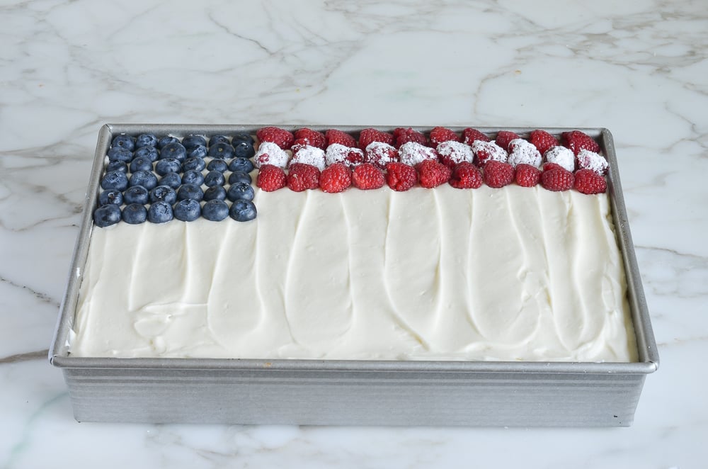 Pan with a rectangle of blueberries, a row of sugared raspberries, and two rows of red raspberries.