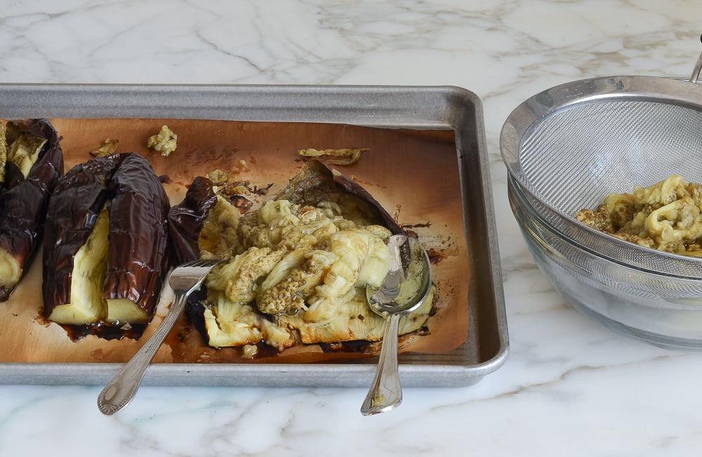 spooning eggplant flesh out of skins