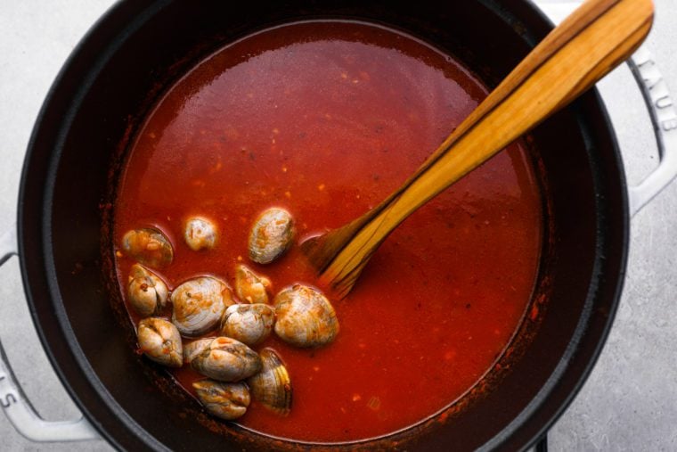 adding the clams to the broth
