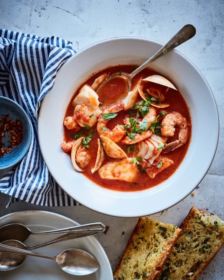Bowl of cioppino with bread.