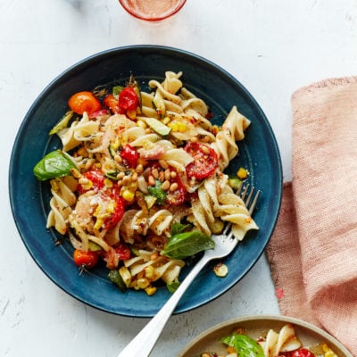 Fork on a blue plate with pasta primavera.