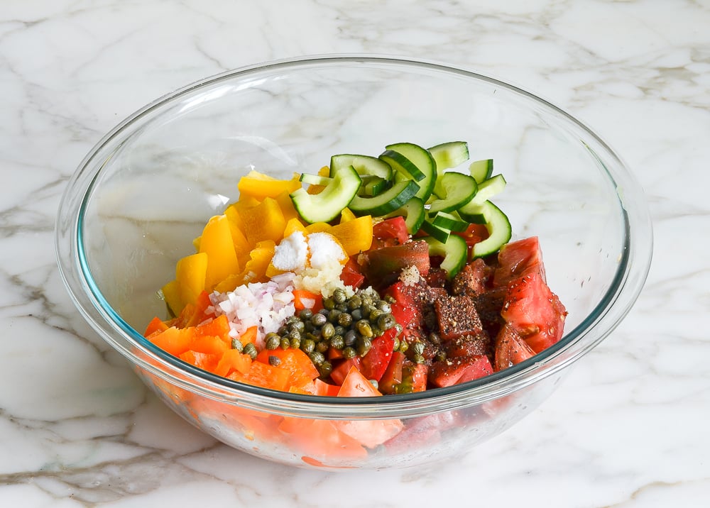 vegetables and dressing ingredients for panzanella salad in mixing bowl