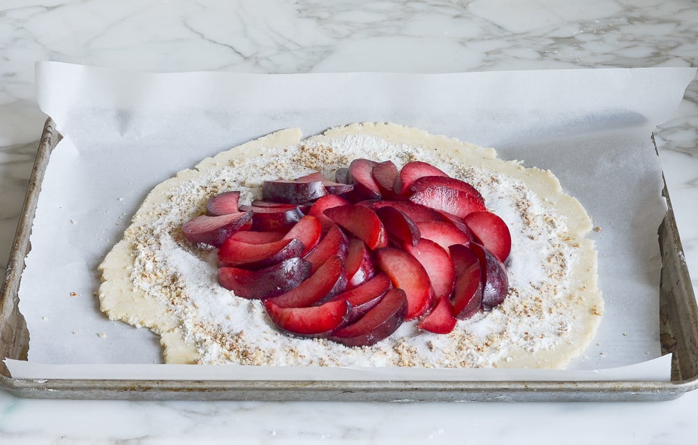 plums arranged in overlapping pattern over dough