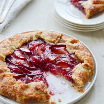 Plum galette on a plate missing a slice.
