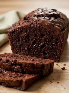Sliced loaf of chocolate zucchini bread on cutting board.