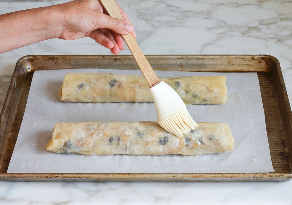 buttering the apple strudels before baking
