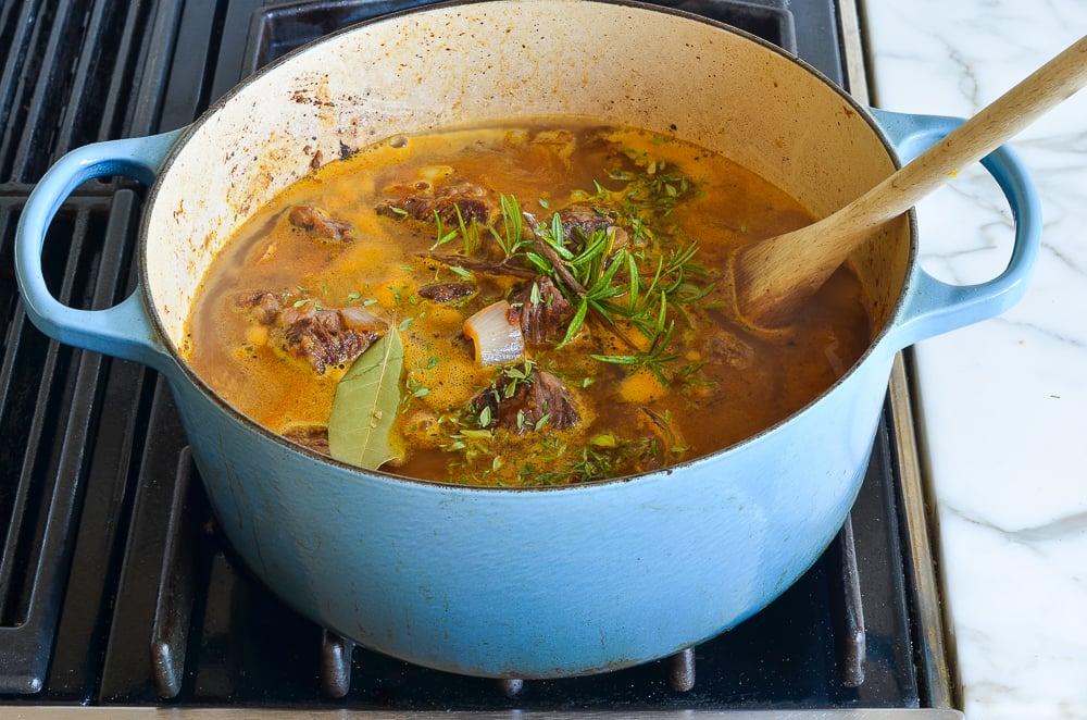 adding the broth, orange juice and herbs