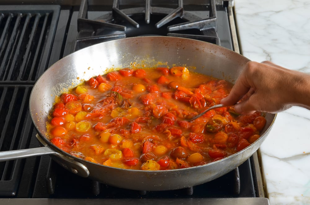 mashing the tomatoes into a chunky sauce