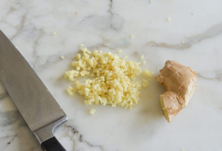 Pile of diced ginger next to a ginger root.