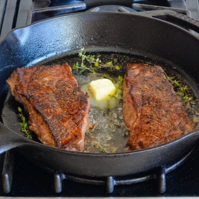 Steak in a skillet with butter.